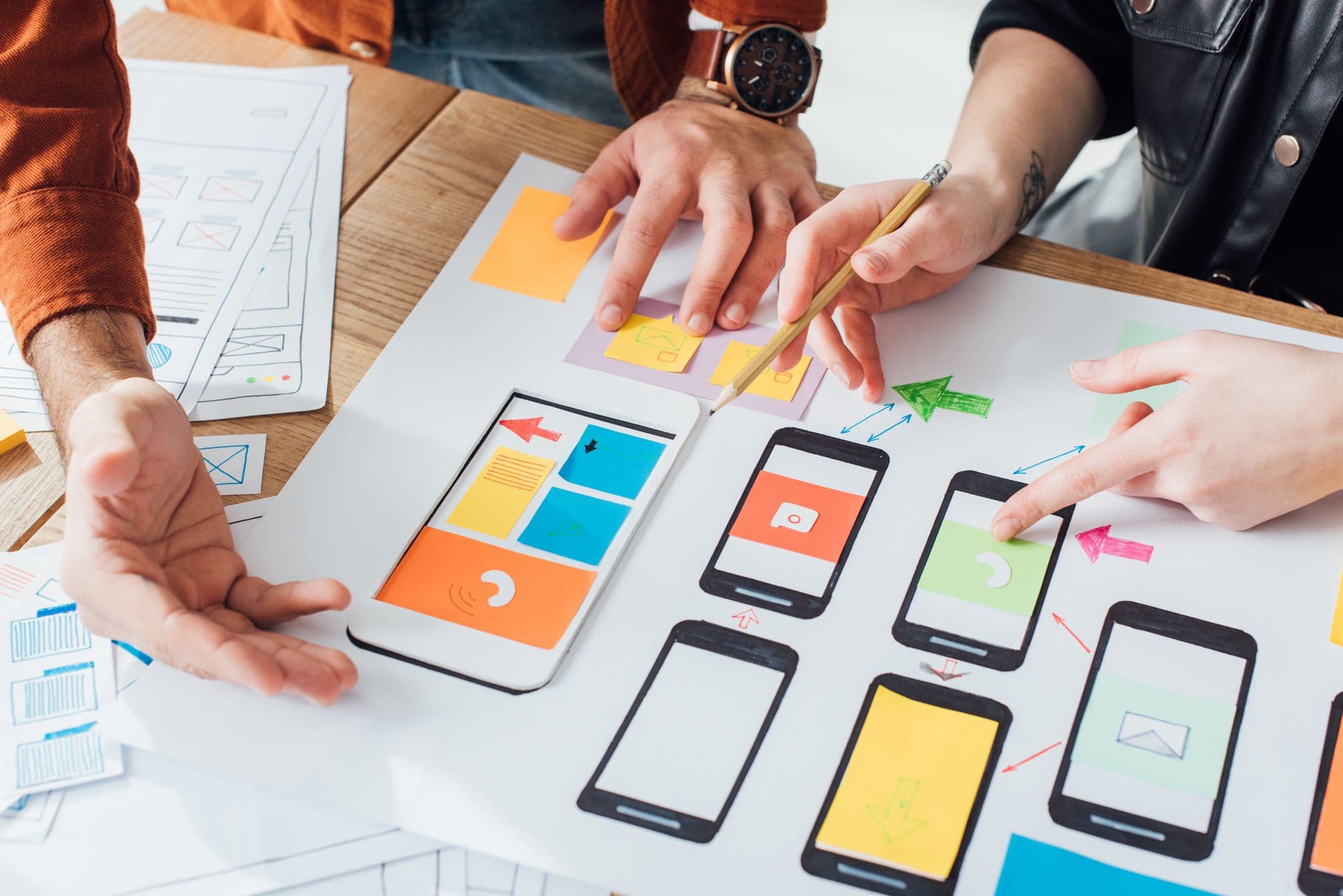 Designers sketching mobile app screens and wireframes on a table