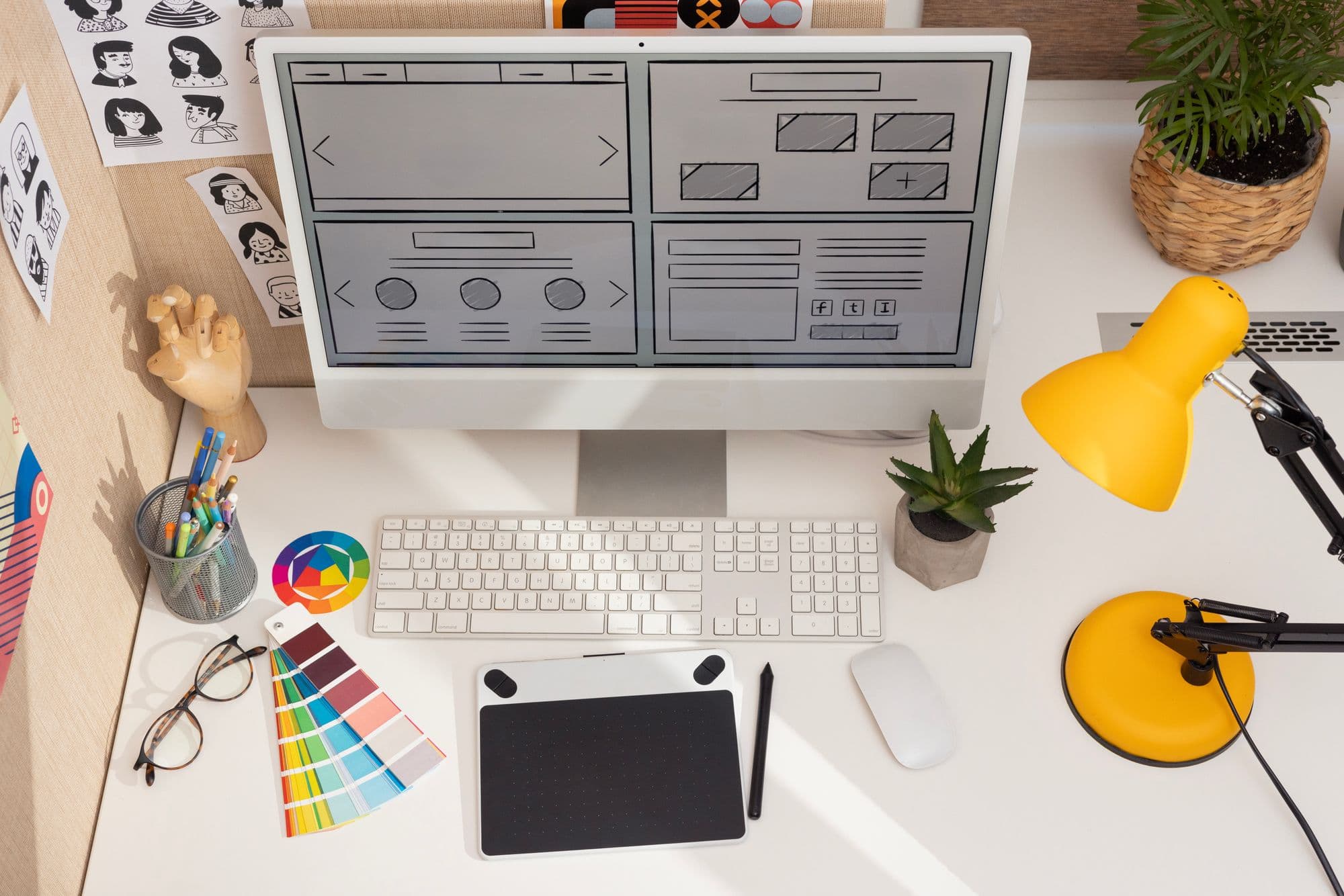Designer's desk with a website wireframe on the monitor